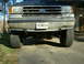 1991 Ford Bronco - The front grille and headlights of a Ford truck are visible, along with its license plate and tires.
