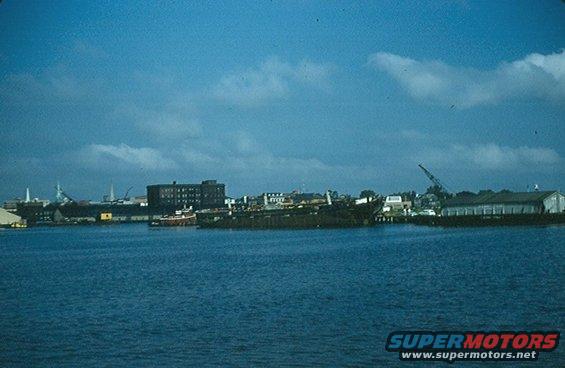 Waterfront industrial scene with ships and buildings under a blue sky
