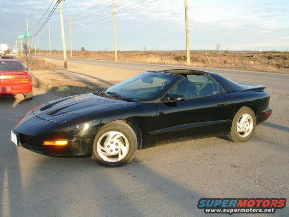 Black Pontiac Firebird parked on roadside with a red car behind it