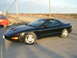 1981 Ford Mustang - A black Pontiac Firebird is parked on the side of a road next to a red car under a cloudy sky.