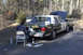 1991 Ford Crown Victoria - A person works on the rear of a black and white police car, possibly a 1991 Ford Crown Victoria, with its hood up.