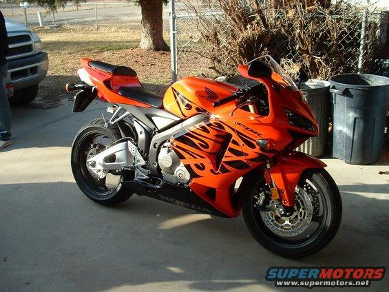 Orange Honda CBR-RR sportbike with flame decals parked on concrete
