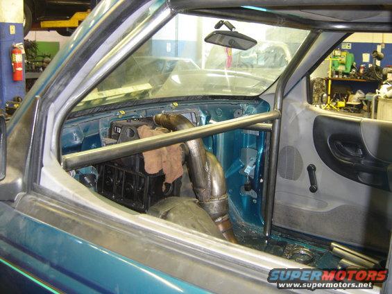 Teal truck interior with roll cage and large exhaust pipe