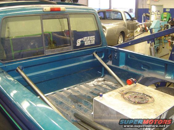 1997 Ford Ranger bed with auxiliary fuel tank and "The Outlaw Diesel Miami.com" sticker on rear window. Another truck is visible in the background