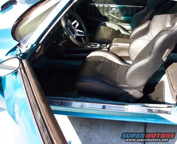 Interior of a blue car with black bucket seats, a steering wheel, and a center console