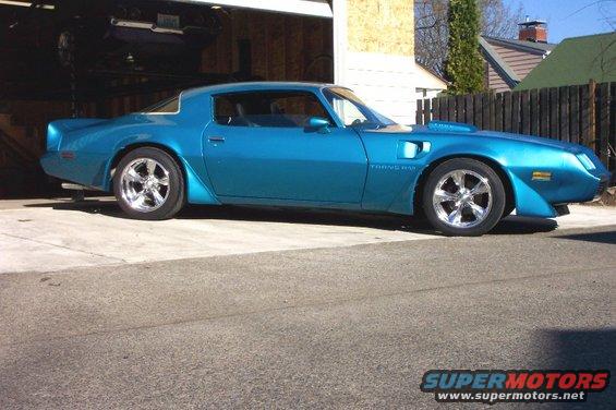 Blue 1979 Pontiac Trans Am parked in front of a garage with another car lifted inside