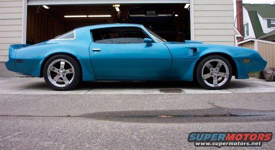 Blue coupe with custom chrome wheels parked in front of a garage