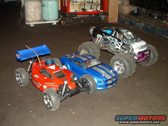 Three RC cars: red buggy, blue muscle car, and monster truck with flame decals