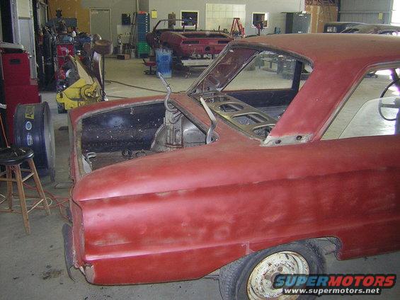 Red 1963 Ford Falcon body, stripped down, in a workshop with other cars
