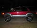 1996 Toyota 4Runner - A red 1996 Toyota 4Runner SUV is parked on a concrete surface at night, showing its lifted suspension and chrome wheels.