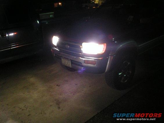 Front view of a 1996 Toyota 4Runner with headlights on, parked next to another vehicle at night