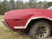 1972 Ford Ranchero - A damaged red car fender is visible from the side, with a dirty tire and wheel.