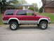 1996 Toyota 4Runner - A red 1996 Toyota 4Runner is shown from the side, parked on a residential street.
