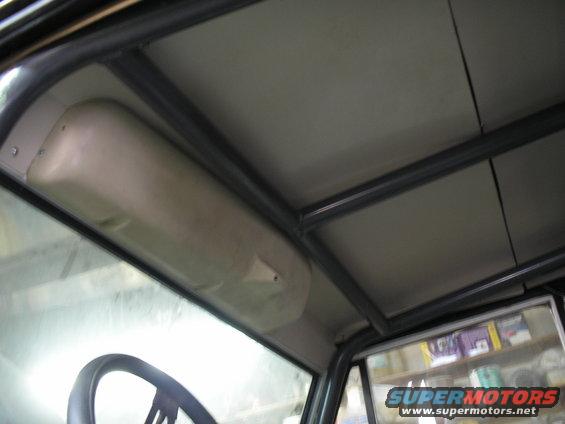 Interior view of a vehicle's roll cage and headliner, with a partial steering wheel visible