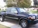 2004 Ford F-150 - This black Toyota Tundra pickup truck is shown from a 3/4 front angle. The 'TUNDRA' badging is visible on the side.