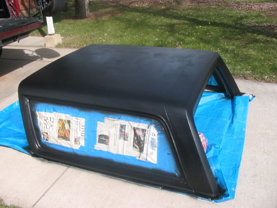 Ford Bronco hardtop covered in newspaper and blue tarp, being prepped for painting