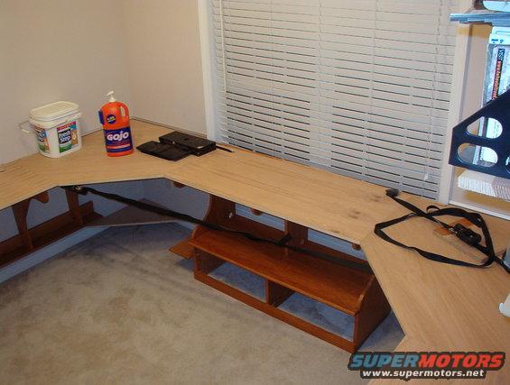 34cornersglued.jpg The plywood was warped, and my cuts weren't as tight as I wanted, so I used a LOT of weight & some ratchet straps to hold the corner panels in place while I screwed them down & the glue dried.  The large holes in the desktop are for cable grommets.