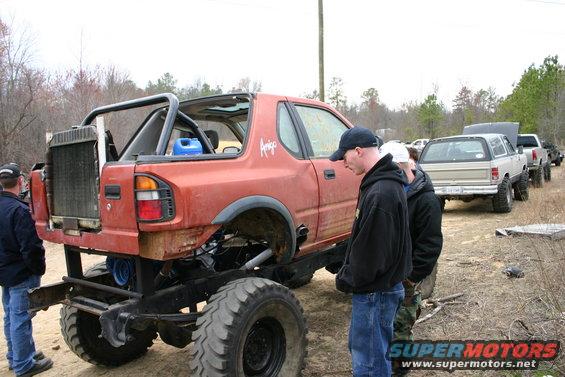 Orange modified truck with exposed radiator and roll cage, viewed from the rear