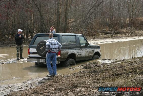 Ford Bronco stuck in mud with people around it