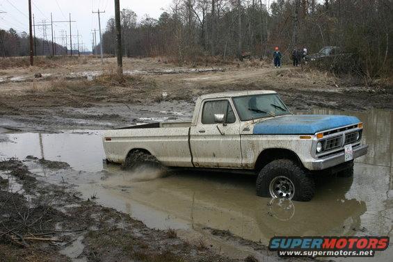 Ford F-Series pickup truck stuck in mud puddle, another vehicle in background