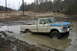 1989 Ford Bronco - This Ford F-Series pickup truck is stuck in a mud puddle with another vehicle visible in the background.