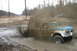 1989 Ford Bronco - A 1973 Ford F-Series truck navigates a muddy obstacle, creating a large splash as another vehicle observes in the distance.