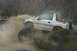 1989 Ford Bronco - This modified Suzuki Samurai is kicking up a huge spray of mud while navigating an off-road course.