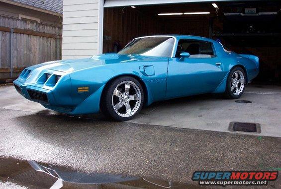 Blue Pontiac Firebird parked in front of an open garage