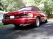 1995 Ford Crown Victoria - A red convertible sedan with a maroon top is shown from the rear quarter angle on a paved driveway.