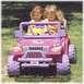 2006 Ford F1 - A pink toy jeep, resembling a Jeep Wrangler, is driven by two young girls outdoors.
