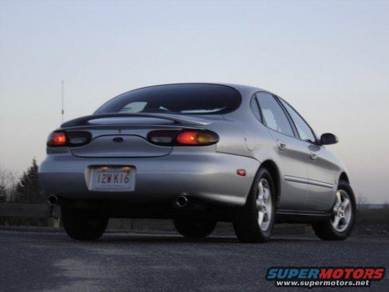 Silver 1999 Ford Taurus sedan, rear 3/4 view, with a spoiler and a license plate reading 12WK16
