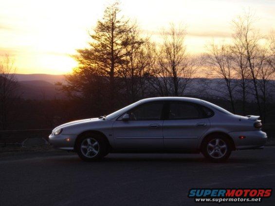 Silver 1999 Ford Taurus sedan parked on road at sunset