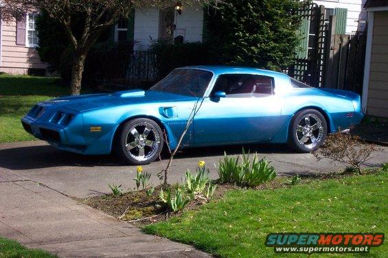 Blue coupe with aftermarket wheels parked on a driveway