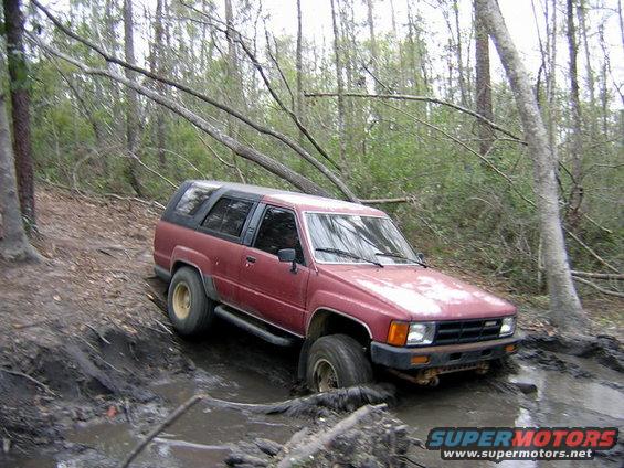 Red 1984 Toyota 4Runner stuck in mud on a wooded trail