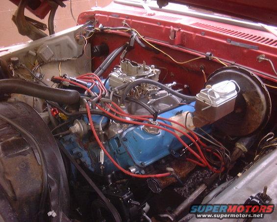 Engine bay showing blue engine block, carburetor, and red spark plug wires