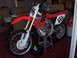 1999 Honda CR250R - A 1999 Honda CR250R dirt bike is parked indoors on a stand.