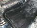 1979 Ford Bronco - Close-up view of the underbody of a vehicle, showing areas of black spray paint and some rust.