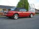 1986 Ford Mustang - Side view of a red 1986 Ford Mustang convertible parked on a street.