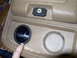1978 Ford Bronco - Close-up of a vehicle's tan center console, showing two cup holders and a small lockable compartment.