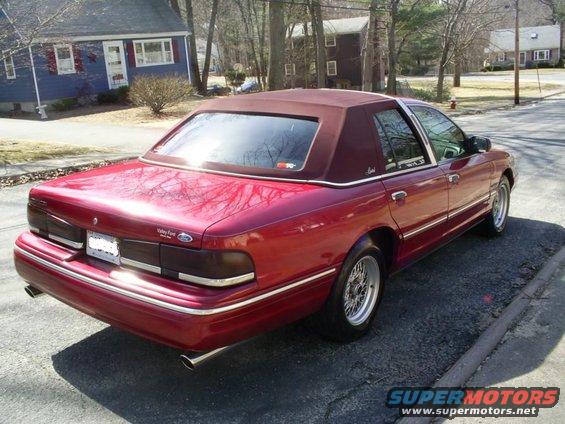 Red 1995 Ford Crown Victoria sedan with a maroon vinyl top, viewed from the rear quarter angle