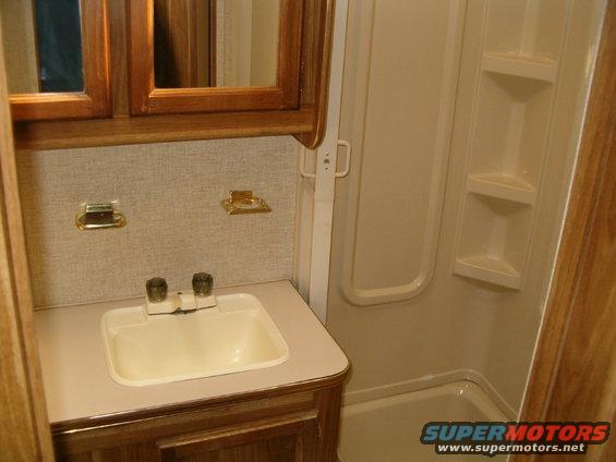 Interior bathroom with sink, shower, and wood cabinetry