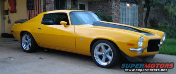 Yellow 1970 Chevrolet Camaro with black racing stripes on the hood, parked in a driveway