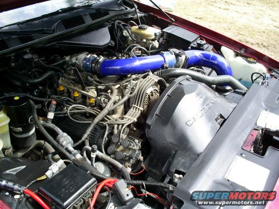 Engine bay with blue intake piping and a black air filter housing with caution text