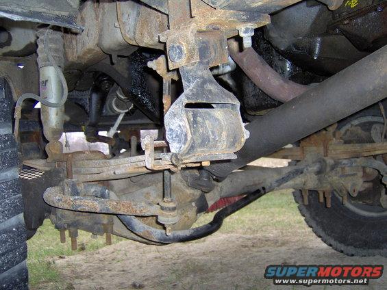 Undercarriage of a truck showing leaf springs, shock absorber, and exhaust pipe