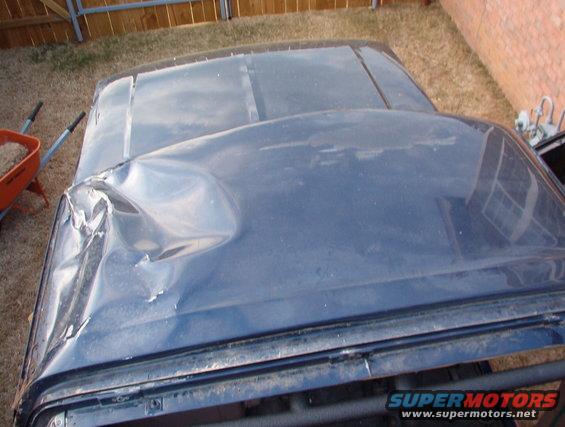 Dented blue vehicle roof panel with visible damage