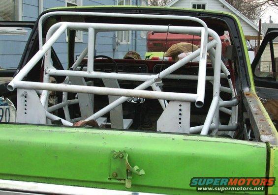White rollcage inside green truck bed, visible steering wheel and dashboard