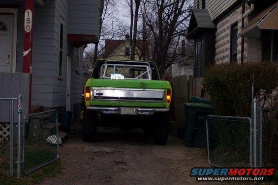 Green 1978 Ford Bronco rear view, lifted, with a roll cage and chrome tailgate trim