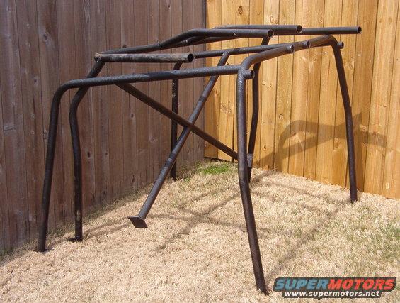 roll cage frame with metal tubes, set up outside against a wooden fence