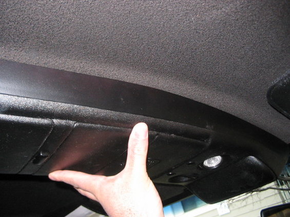 Hand pressing on the overhead console storage compartment of a vehicle