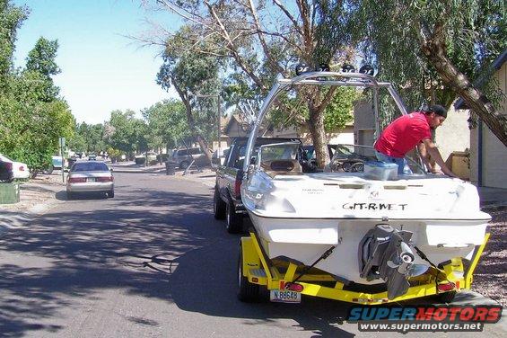 Rear view of a boat on a trailer, towed by a truck, with a person working on the boat